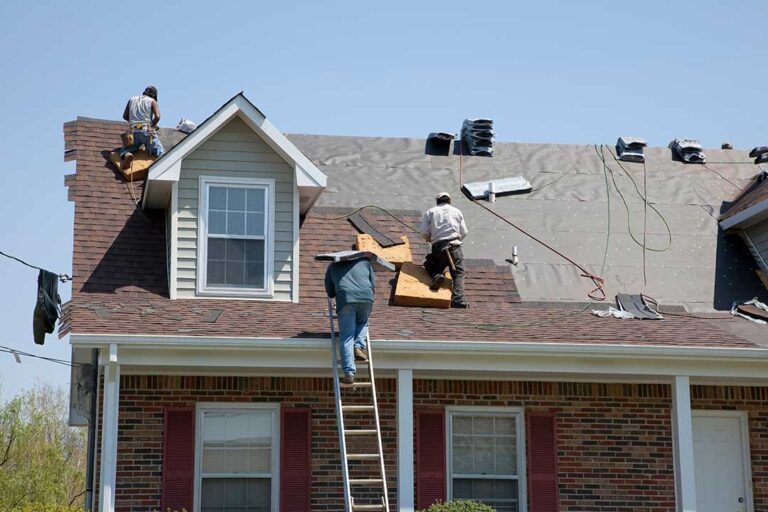A person using binoculars to inspect a residential roof from the ground on a sunny day.