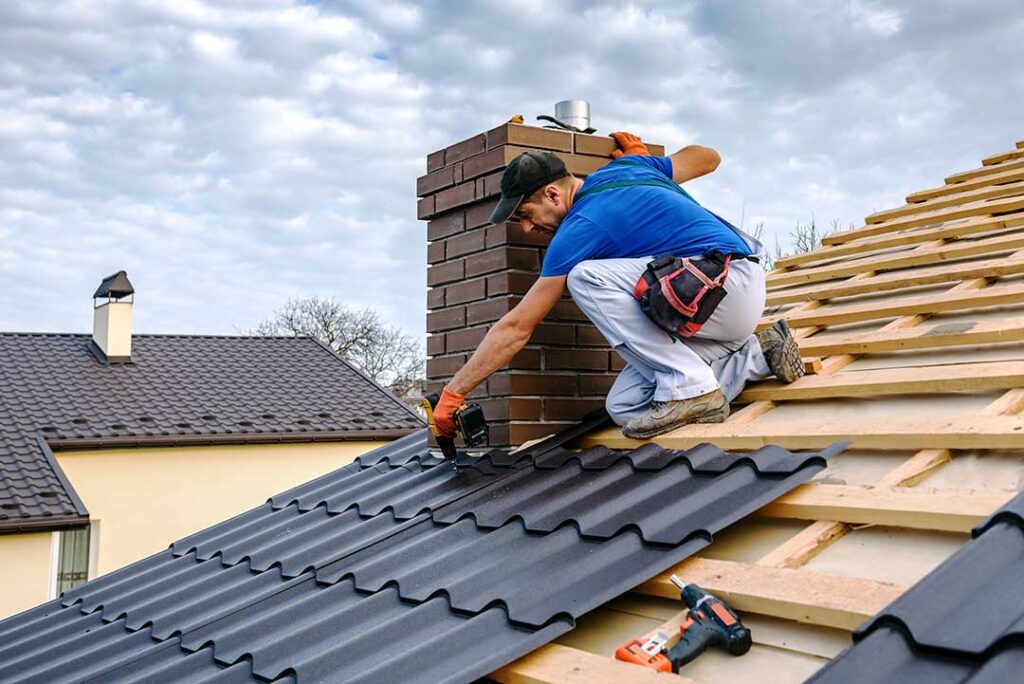 A person on a ladder inspecting roof shingles next to a two-story home with mature trees nearby.